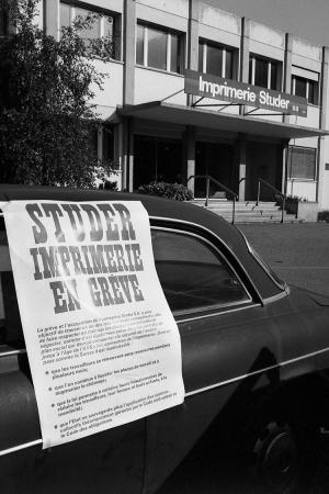 photo en noir et blanc d'une affiche collée sur une voiture annonçant une imprimerie en grève