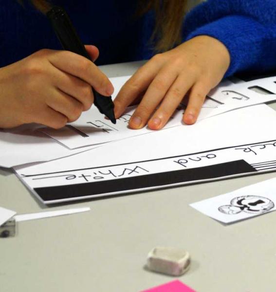 un enfant tient dans la main un stylo feutre et s'apprête à dessiner sur une feuille