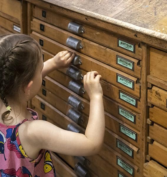 jeune visiteuse ouvrant un tiroir de casse d'imprimerie