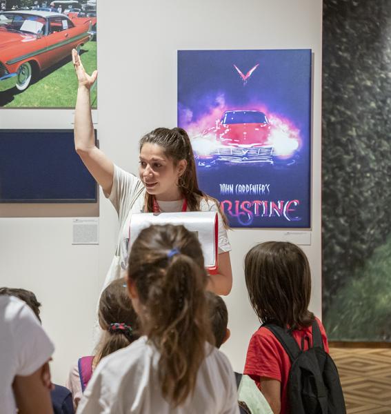 médiatrice entourée de jeunes visiteurs en salle d'exposition