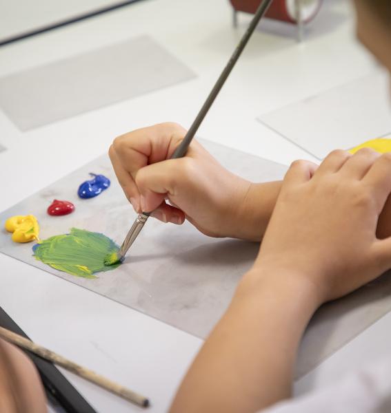 enfant apposant de la peinture sur une feuille au moyen d'un pinceau