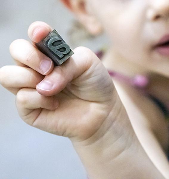 main d'enfant tenant un caractère mobile d'imprimerie