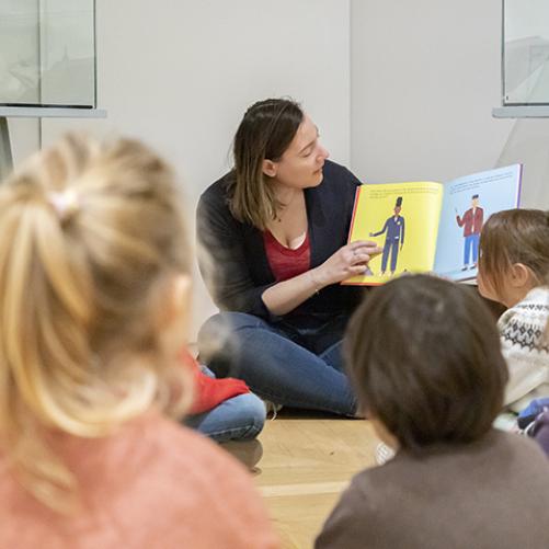 médiatrice en train de lire un livre illustré à des enfants assis par terre