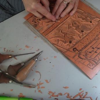 deux mains gravent une plaque de bois