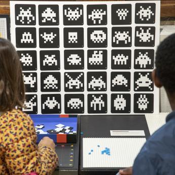 deux enfants vus de dos regardant des exemples de Space Invaders