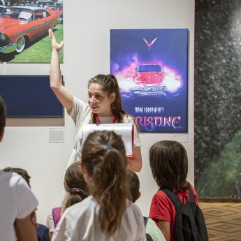 médiatrice entourée de jeunes visiteurs en salle d'exposition