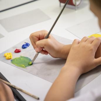 enfant qui tient un pinceau, en train de peindre