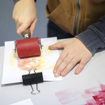 enfant en train d'utiliser un rouleau encré pour réaliser une image en estampage