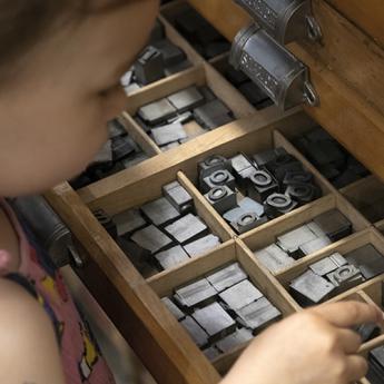 enfant qui tient un caractère mobile d'imprimerie issu d'une casse