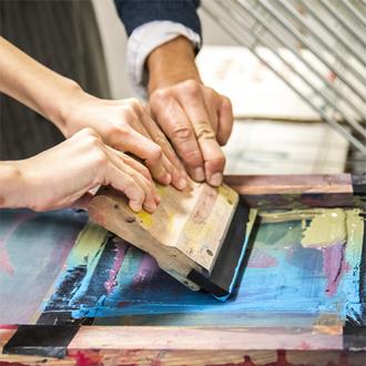 mains d'enfants s'essayant à la sérigraphie avec encre bleue