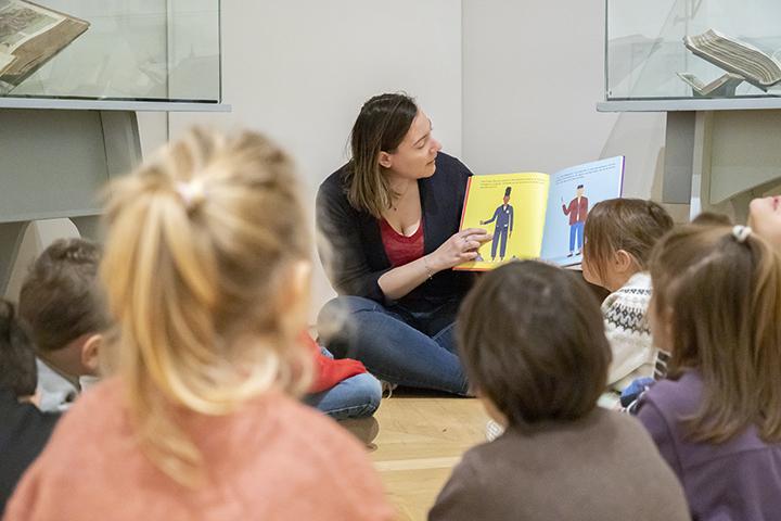 médiatrice en train de lire un livre illustré à des enfants assis par terre