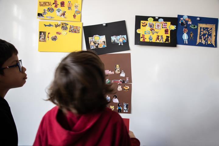 faire musée à l'école : des élèves devant un tableau avec leurs réalisation exposées