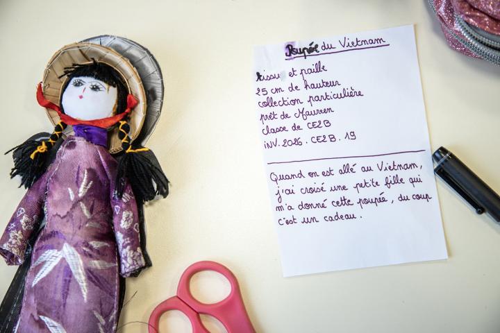 l'objet d'un élève, une poupée accompagné d'une note le décrivant